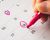 A hand holding a pink marker circles two dates on a calendar.